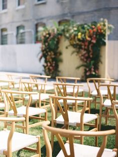 rows of wooden chairs sitting on top of a lush green field next to a building