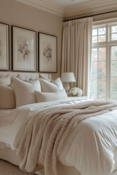 a large bed in a bedroom next to a window with pictures on the wall above it