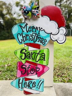 a wooden sign that says merry christmas santa stop here and has an arrow on it