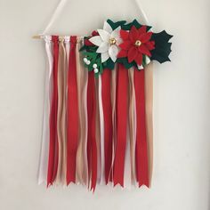 a christmas decoration hanging on a wall with poinsettis and ribbons attached to it