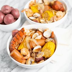 two white bowls filled with seafood and potatoes