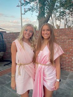 two girls in pink dresses standing next to each other