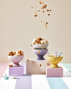 three bowls filled with food sitting next to each other on top of colorful blocks in front of a white wall