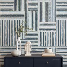 a blue and white wall with two vases next to each other on top of a dresser