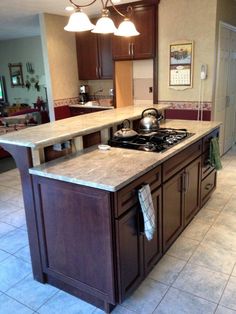 a kitchen with an island, stove top and sink in it's center area