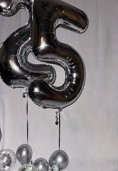 the number five balloon is hanging from the ceiling with silver balloons attached to it's sides