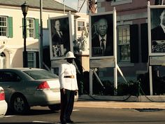 a man standing on the side of a road in front of some posters and cars