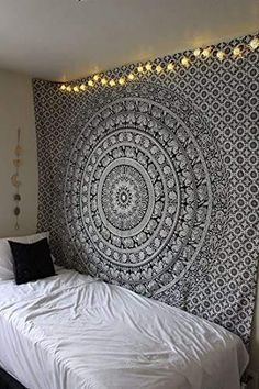 a bed sitting under a large black and white tapestry on the side of a wall