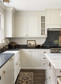 a kitchen with white cabinets and black counter tops, an area rug on the floor