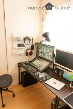 there is a desk with a computer and headphones on it in the corner of this room