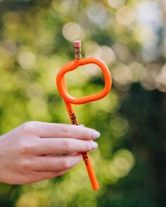 a person holding an orange object in their hand with the letter o on it's tip