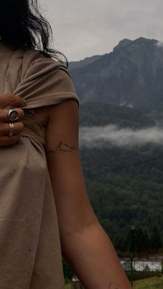 a woman with her arm wrapped around the back of her body and mountains in the background