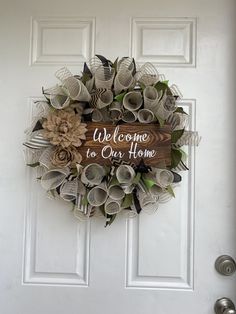 a welcome to our home wreath hanging on the front door with paper flowers and leaves