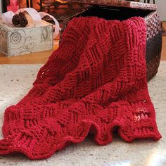 a red knitted blanket sitting on top of a floor next to a fire place