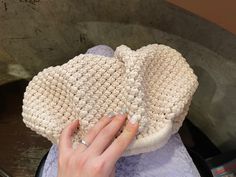 a woman's hand holding onto a crocheted hat