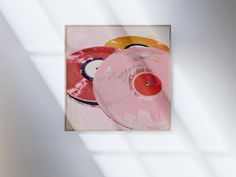 an abstract painting with pink and yellow circles in the center, on a white wall