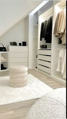 an attic bedroom with white furniture and open closets, including a large rug on the floor