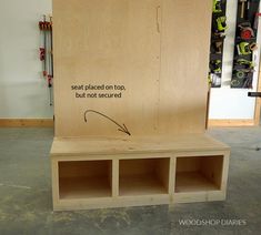 a wooden bench sitting inside of a garage next to a wall with tools on it