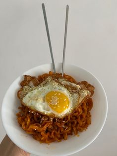 a white plate topped with noodles and an egg