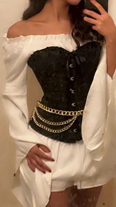 a woman wearing a black and white corset with gold chains on her waist