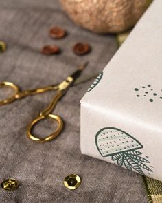 a pair of scissors sitting on top of a table next to a box with buttons