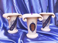 two white vases sitting on top of a blue cloth