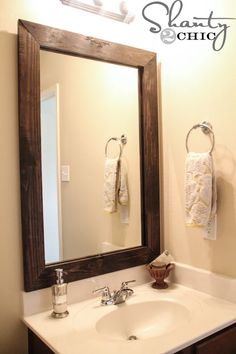 a bathroom sink sitting under a mirror next to a wooden framed medicine cabinet with towels hanging on it