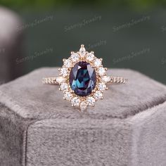 a blue and white diamond ring sitting on top of a gray stone block with diamonds around it