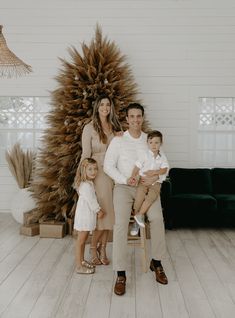 a family posing for a photo in front of a large fake sunflower tree with their two children