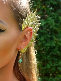 a close up of a person wearing ear clips with leaves on it's ears