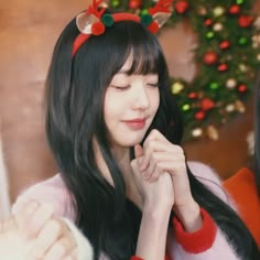 a woman with long black hair wearing reindeer antlers on her head and looking to the side