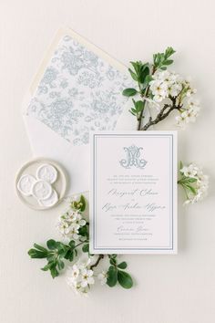 the wedding stationery is laid out on top of an envelope and some white flowers