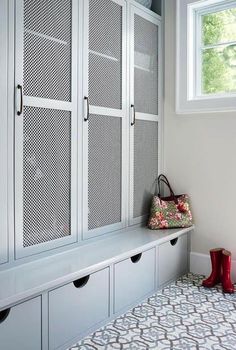 a room with white cabinets and red boots on the floor, next to a window