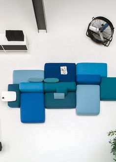 a blue couch sitting next to a wall mounted fan