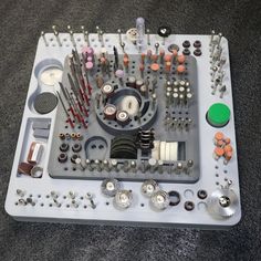 an assortment of sewing tools displayed on top of a white board with screws and thread spools