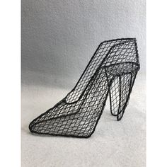 a black wire sculpture on top of a white floor next to a pair of high heeled shoes