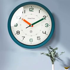 a blue and white clock hanging on the wall next to a vase filled with flowers