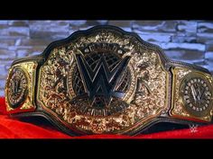 a gold and black wrestling belt sitting on top of a red velvet covered floor next to a brick wall