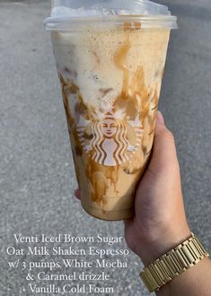 a hand holding up a starbucks drink with the words, ventted iced brown sugar out milkshake espresso w / 3 pumps white mocha & caramel drizze vanilla cold foam