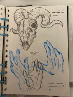 an open notebook with drawings of rams and hands