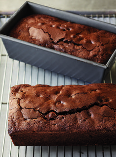 two loafs of chocolate cake sitting on top of a cooling rack next to each other