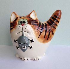 a ceramic figurine of a cat with a mouse on it's back