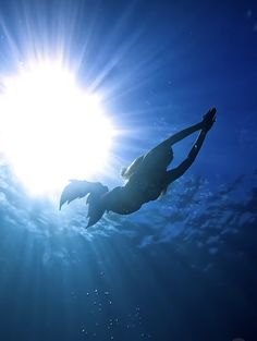 a woman swimming in the ocean with sun shining above her head and water around her