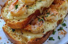 two pieces of bread with shrimp and cheese on them, sitting on a white plate