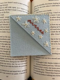 an origami bookmark made out of felt and thread with flowers on it