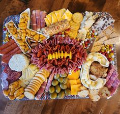 a platter filled with different types of meats, cheeses and crackers