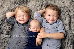 two young boys laying on top of each other with their arms around one another's head