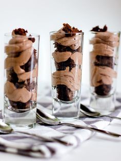 three glasses filled with dessert sitting on top of a table