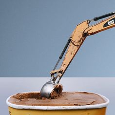 an excavator scooping chocolate into a yellow bucket with blue sky in the background