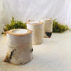 three white candles sitting on top of snow covered ground